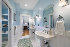 Full bathroom featuring a wainscoted wall, two sinks, and light tile patterned floors