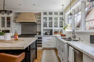 Dual tone kitchen featuring two tone cabinets, glass fronted cabinets, hanging light fixtures, tasteful backsplash, and stainless steel appliances