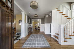Entryway with wainscoting, a decorative wall, and dark wood-style floors