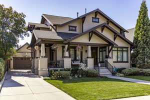 Craftsman house featuring a shingled roof, covered porch, a front yard, a garage, and concrete driveway