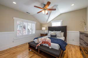 Bedroom with light wood-style flooring, wainscoting, lofted ceiling, a ceiling fan, and recessed lighting