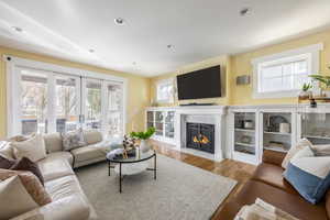 Living room with a fireplace with flush hearth, light wood-style flooring, and recessed lighting