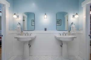 Bathroom with wainscoting, connected bathroom, and two sinks