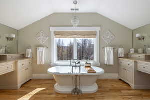 Bathroom with vanity, light wood finished floors, a freestanding tub, and hanging lights
