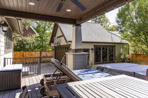 Wooden terrace featuring a covered hot tub, ceiling fan, and outdoor dining area