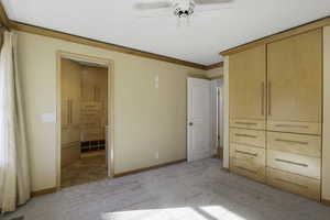 Unfurnished bedroom with light carpet, a ceiling fan, and crown molding