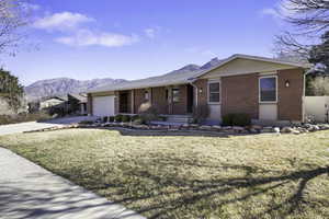 Ranch-style home featuring brick siding, covered porch, an attached garage, and a mountain view