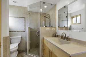 Full bath featuring a shower stall, vanity, and tile walls