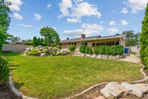 Rear view of house with a gate, a chimney, and stucco siding