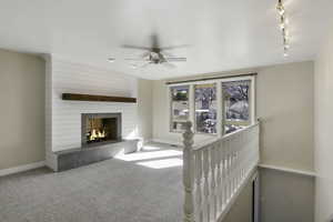 Living room with a fireplace, carpet flooring, and a ceiling fan