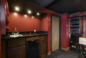Indoor wet bar with black fridge, tile counters, and dark wood finished floors