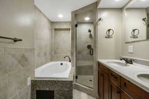 Bathroom with a tub with jets, double vanity, a shower stall, and recessed lighting
