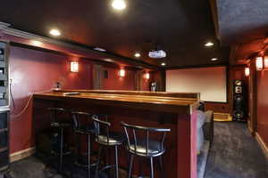 Indoor dry bar featuring wooden counters, dark carpet, and recessed lighting