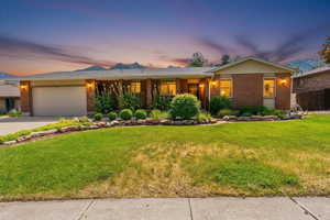 Ranch-style home featuring brick siding, a lawn, an attached garage, and driveway