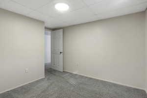 Spare room featuring a paneled ceiling and light carpet