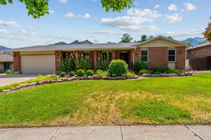 Ranch-style house with a mountain view, brick siding, a garage, and concrete driveway