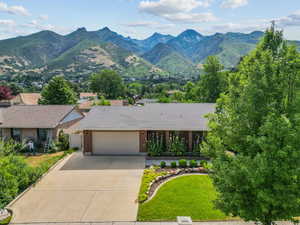 View of front of property with concrete driveway, a mountain view, an attached garage, brick siding, and roof with shingles