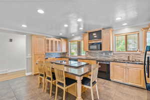 Kitchen featuring light wood finish cabinets, ornamental molding, black appliances, dark stone countertops, and glass fronted cabinets