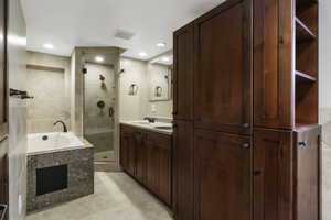 Bathroom featuring double vanity, a garden tub, a shower stall, light tile patterned floors, and recessed lighting