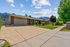 Ranch-style home with a mountain view, driveway, brick siding, a gate, and an attached garage