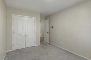 Unfurnished bedroom featuring a closet and light carpet