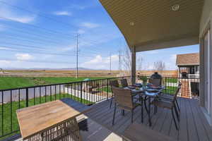 Deck with outdoor dining area, a lawn, a rural view, and a mountain view