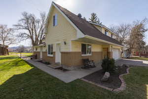 View of home's exterior with brick siding, a yard, roof with shingles, and driveway