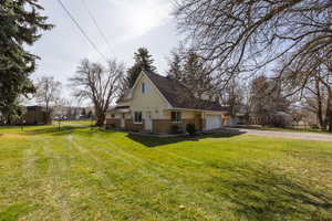 View of side of home featuring driveway, a yard, brick siding, and a garage