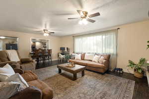 Living area featuring hardwood / wood-style floors, ceiling fan, and a textured ceiling