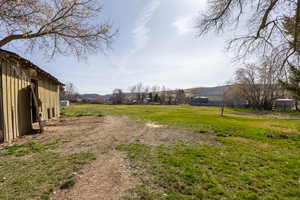 View of grassy yard featuring an outdoor structure and a mountain view