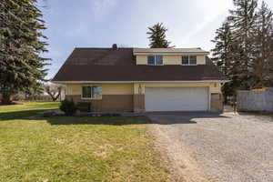 View of front of home featuring gravel driveway, brick siding, and a garage