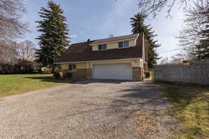 View of front of house with driveway, a chimney, a garage, and brick siding
