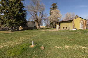 View of grassy yard featuring an outbuilding and a pole building