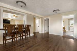 Dining area featuring dark wood-style flooring, a ceiling fan, and a textured ceiling