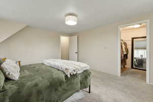 Bedroom with a walk in closet and carpet floors