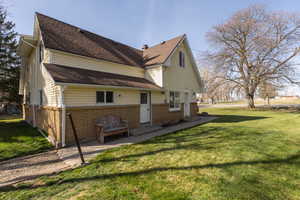 Rear view of house featuring a lawn, brick siding, and a shingled roof