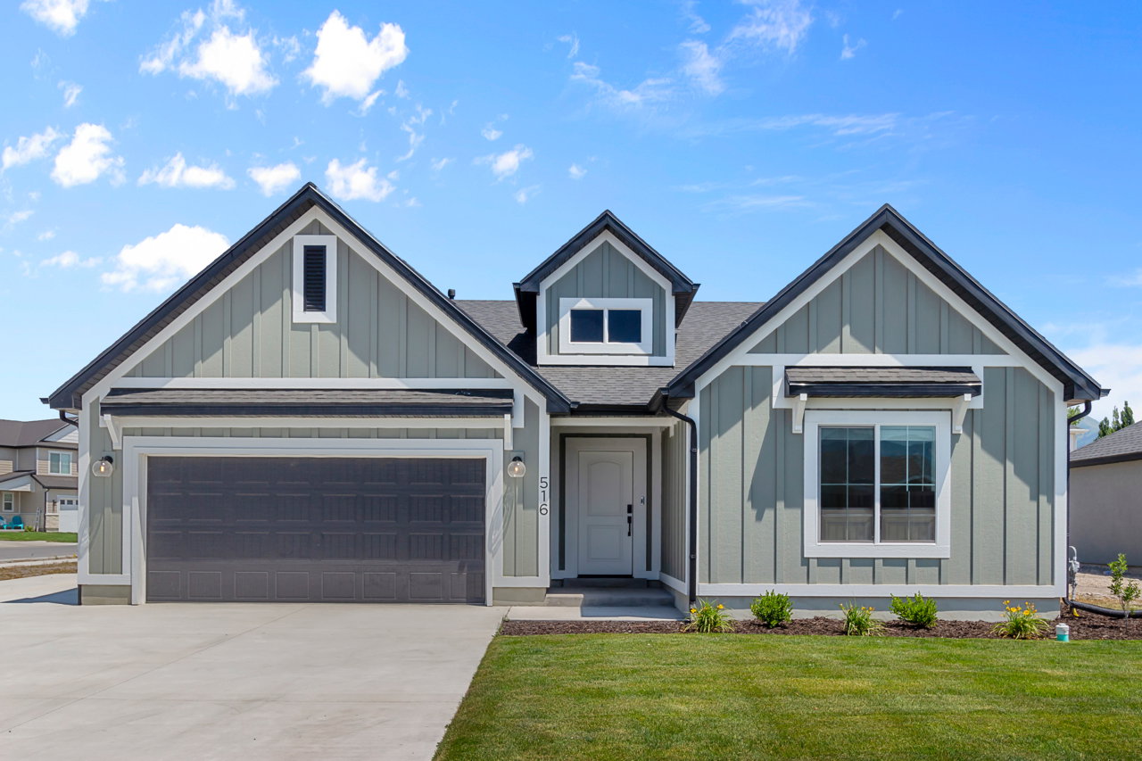 View of front facade with roof with shingles, driveway, board and batten siding, and a front yard