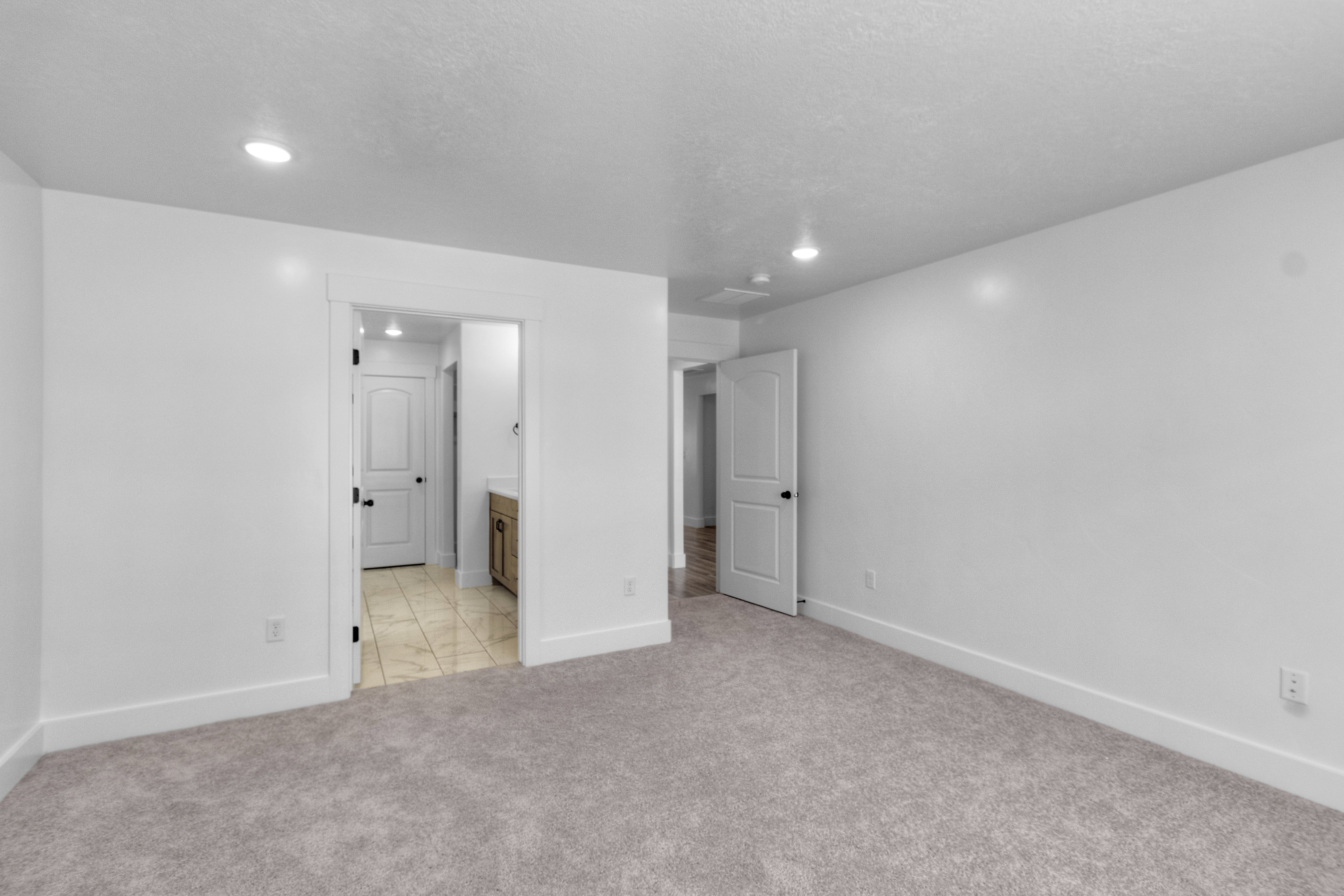 Unfurnished bedroom featuring ensuite bathroom and light colored carpet