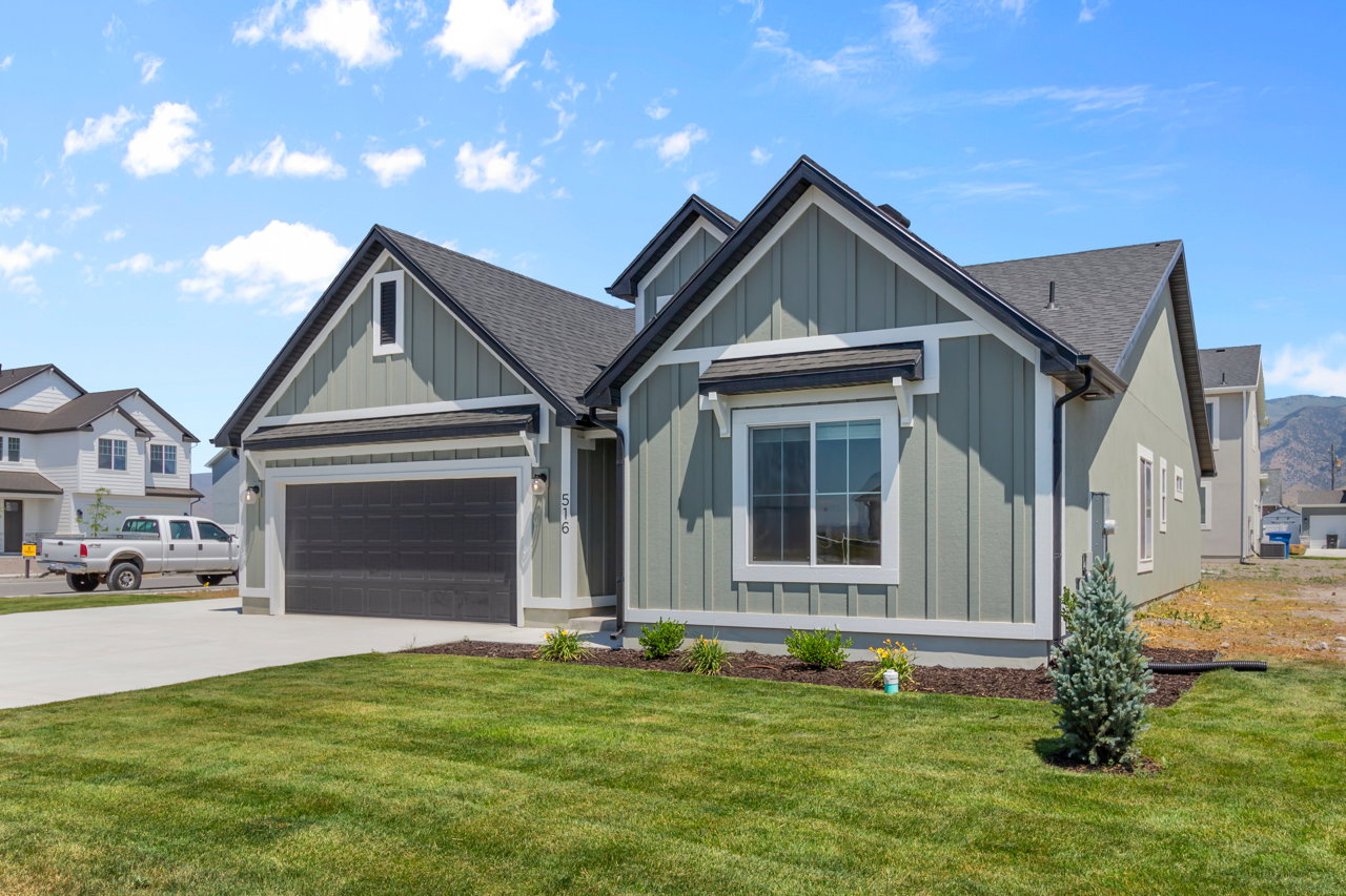 View of front facade featuring board and batten siding, driveway, roof with shingles, and a front yard