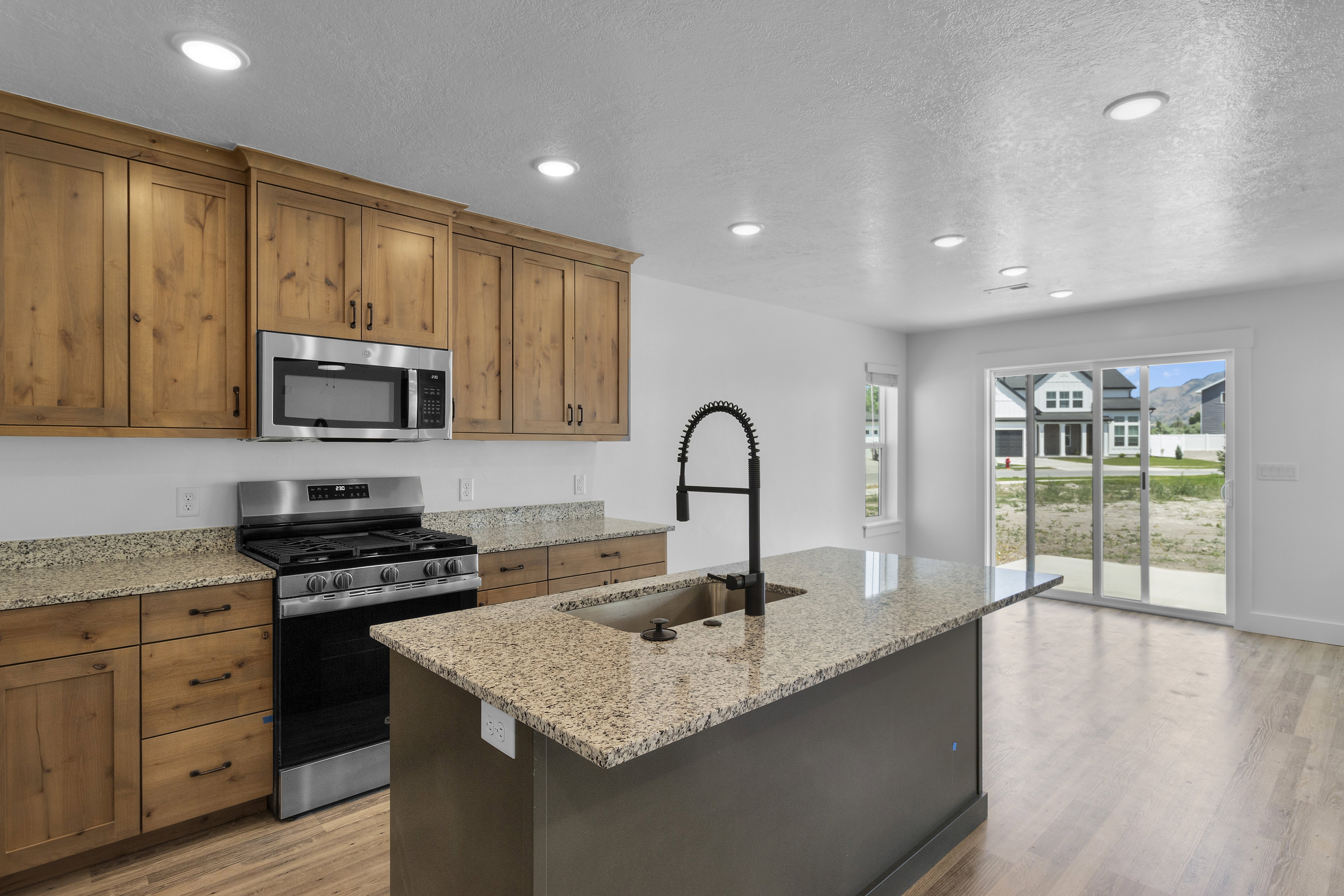 Kitchen featuring stainless steel appliances, light stone countertops, a center island with sink, light wood-type flooring, and recessed lighting