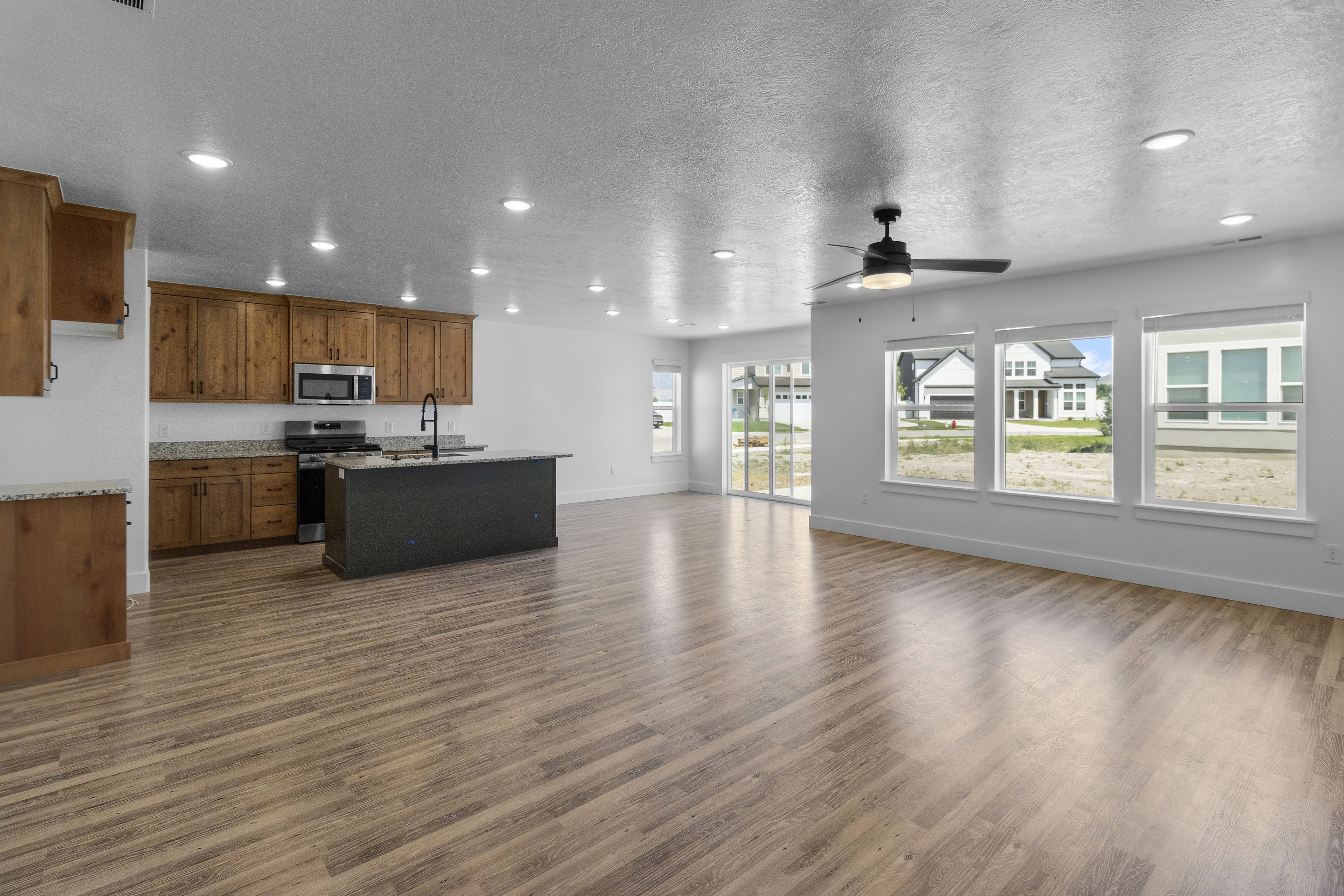 Kitchen with open floor plan, recessed lighting, a textured ceiling, stainless steel appliances, and wood finish cabinetry