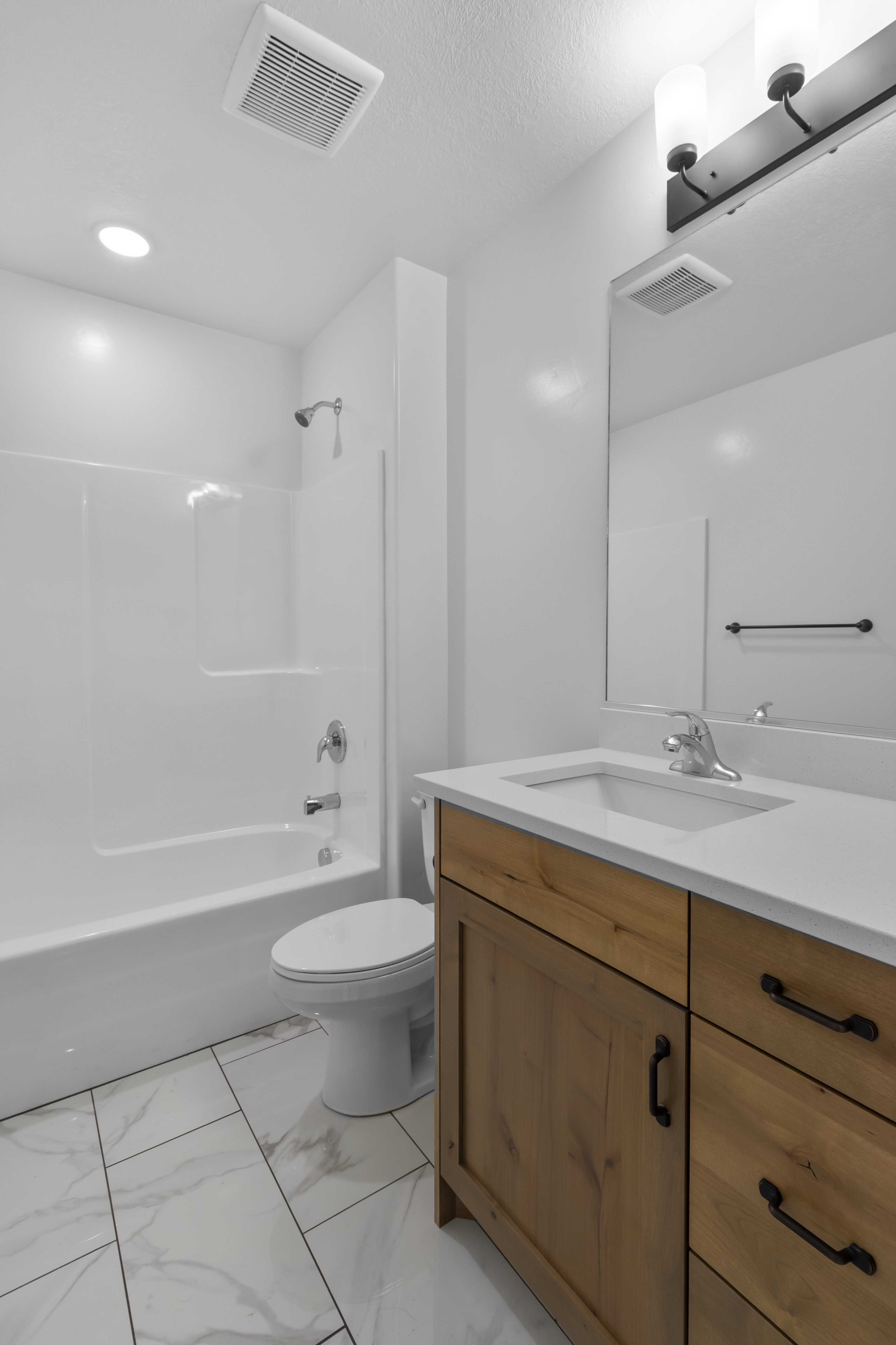 Bathroom with vanity, shower / washtub combination, and light marble finish flooring