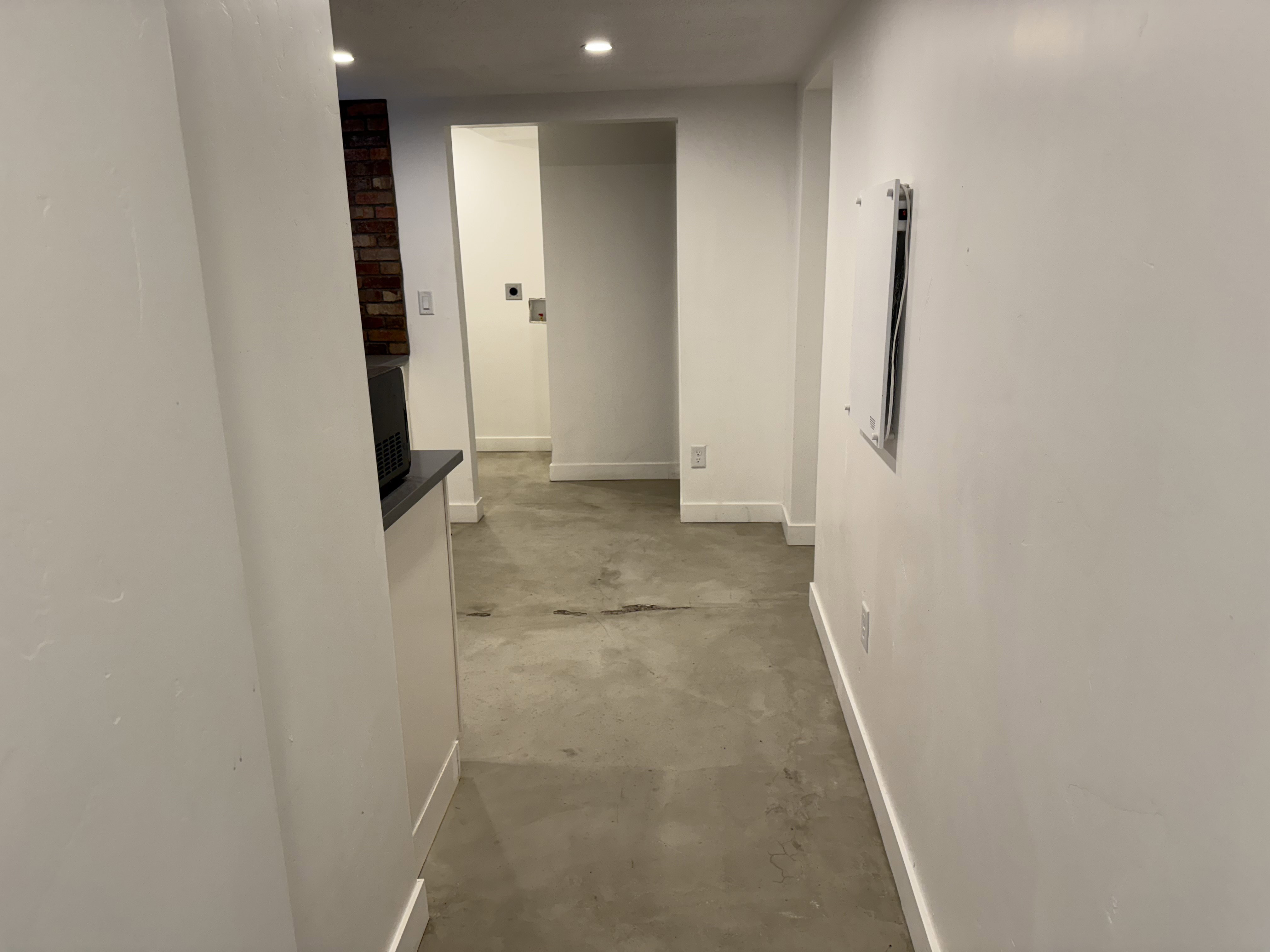 Hall featuring unfinished concrete flooring, recessed lighting, and electric panel