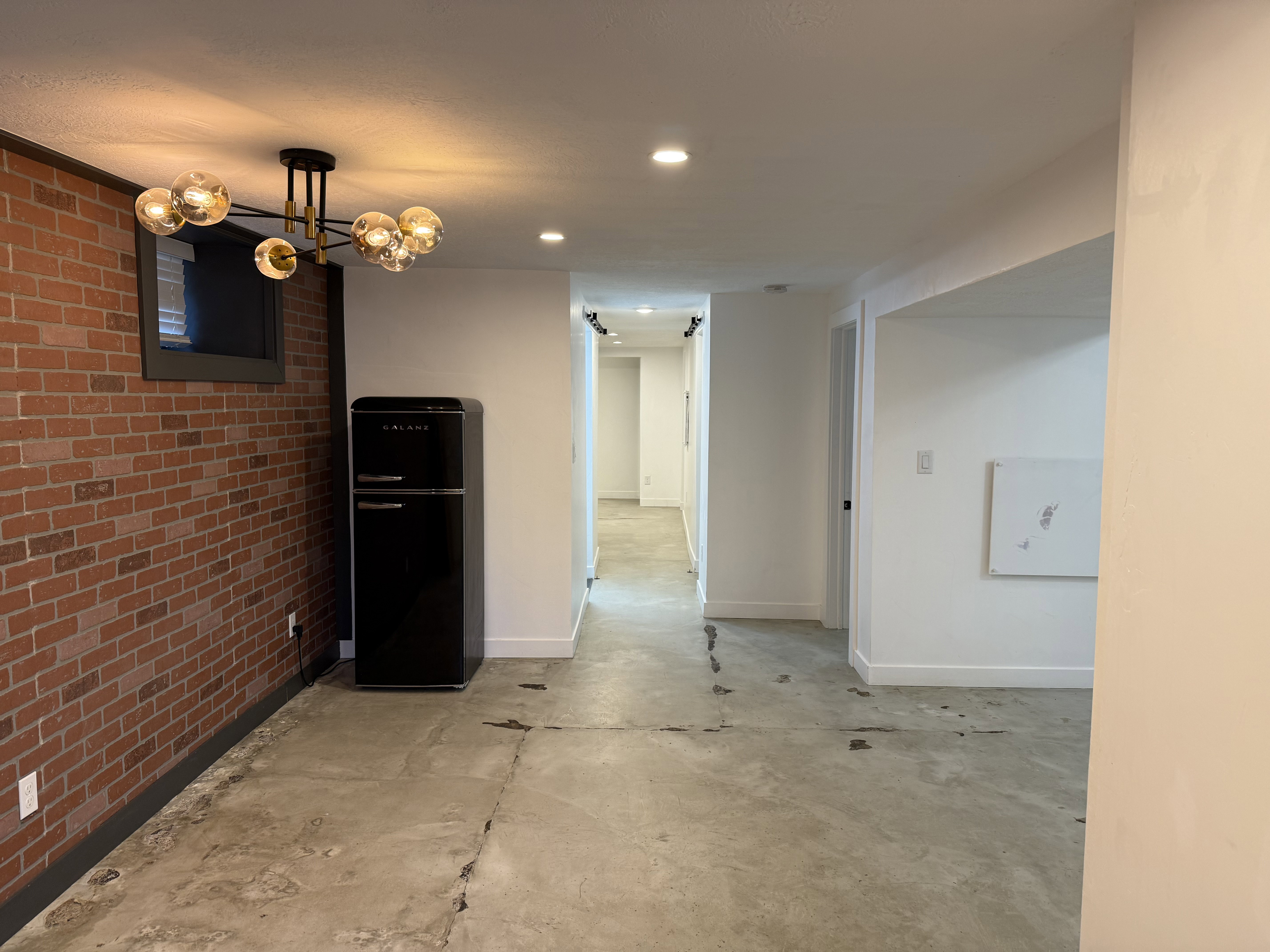 Unfurnished dining area with brick wall, unfinished concrete flooring, and recessed lighting