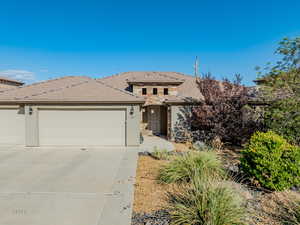 View of front facade with a garage, driveway, stucco siding, and a tiled roof