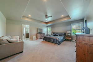 Bedroom with light carpet, ceiling fan, a tray ceiling, and recessed lighting