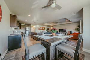 Kitchen with dark wood finish cabinetry, a center island, stainless steel refrigerator with ice dispenser, ceiling fan, and arched walkways