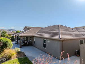 View of side of home with stucco siding, a tile roof, a mountain view, and covered porch