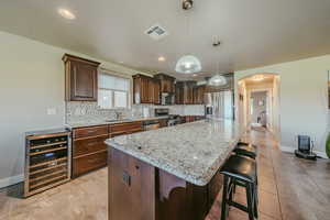 Kitchen with arched walkways, backsplash, light stone countertops, and wine cooler