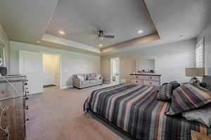 Bedroom with light carpet, a ceiling fan, a tray ceiling, and recessed lighting